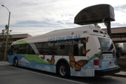 FILE - An electric bus sits under a charging station in Azusa, California, Nov.16, 2017.