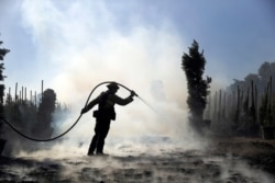 Morgan Clark, a firefighter with the Oxnard Fire Dept., hoses down hot spots created by the Easy Fire on a farm, Oct. 30, 2019, in Simi Valley, California.