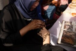 A Sudanese woman applies henna to a Yemeni girl's hand during an event marking the U.N.'s International Refugee Day, in Cairo, Egypt, June 20, 2019.