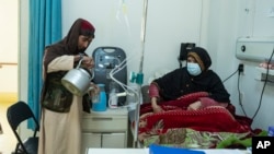 FILE - An Afghan man prepares tea for a relative being treated for COVID-19 in the Afghan-Japan Hospital in Kabul on Dec. 9, 2021. Afghanistan's health care system is on the brink of collapse and able to function only with a lifeline from international aid organizations.
