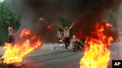 FILE - Anti-government protesters set fires and close a street during a demonstration in Baghdad, Iraq, Oct. 6, 2019. 
