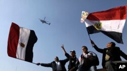 Người Ai Cập vẫy cờ chào đón 1 máy bay trực thăng quân đội bay ngang qua Quảng trường Tahrir, tâm điểm của cuộc nổi dậy 3 năm trước, ở Cairo, Ai Cập, thứ Bảy 25/1/2014
