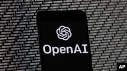 ARCHIVO - El logotipo de OpenAI aparece en un teléfono celular frente a la pantalla de una computadora, el 9 de marzo de 2023, en Boston. 