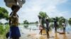 FILE - A family try to cross a flooded area after the Nile river overflowed after continuous heavy rain which caused thousands of people to be displaced in Bor, central South Sudan, Aug. 9, 2020. 