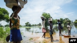 FILE - A family try to cross a flooded area after the Nile river overflowed after continuous heavy rain which caused thousands of people to be displaced in Bor, central South Sudan, Aug. 9, 2020. 