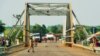 Two SPLA soldiers guard the bridge that divides South Sudan and Uganda. The Ugandan police say they have tightened their borders and aren't letting many through. (L. Paulat/VOA)