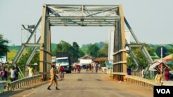 Two SPLA soldiers guard the bridge that divides South Sudan and Uganda. The Ugandan police say they have tightened their borders and aren't letting many through. (L. Paulat/VOA)