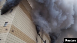 FILE - Members of the Emergency Situations Ministry work to extinguish a fire in a shopping mall in the Siberian city of Kemerovo, Russia.