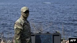 Ukrajinski službenik Glavne uprave za obavještajne poslove Ministarstva odbrane Ukrajine stoji ispred pomorskog drona Magura tokom demonstracije za novinare na neotkrivenoj lokaciji u Ukrajini 11. aprila 2024.