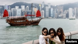 Tourists take photos in front of Victoria Harbor in Hong Kong on April 29, 2024. China's Individual Visit Scheme allows residents from some areas to travel to Hong Kong on their own, rather than in a tour group.