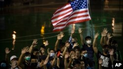 Para demonstran pro-demokrasi di Hong Kong melambaikan bendera Amerika dalam aksi protes hari Selasa (15/10). 