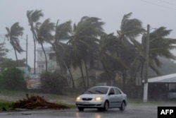 Un automóvil circula en una carretera cuando la tormenta tropical Laura azota Guayama, Puerto Rico, el 22 de agosto de 2020.