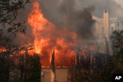 Fueled by high winds, the Palisades Fire burns through property in the Pacific Palisades neighborhood of Los Angeles, Jan. 8, 2025.