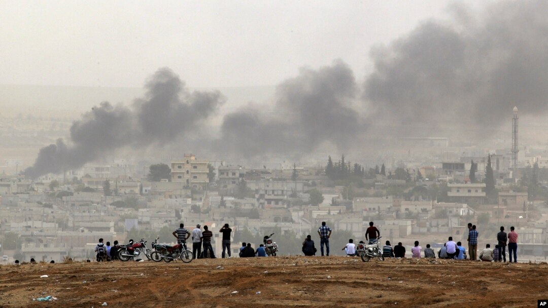 Warga di Suruc, perbatasan Turki-Suriah, menyaksikan asap membubung akibat pertempuran di kota Kobani, Suriah (11/10). (AP/Lefteris Pitarakis)