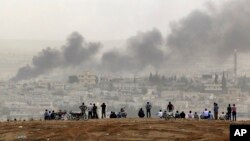 Warga di Suruc, perbatasan Turki-Suriah, menyaksikan asap membubung akibat pertempuran di kota Kobani, Suriah (11/10). (AP/Lefteris Pitarakis)