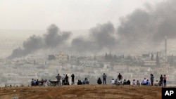 Curiosos observan desde una colina los combates en Kobani, Siria.