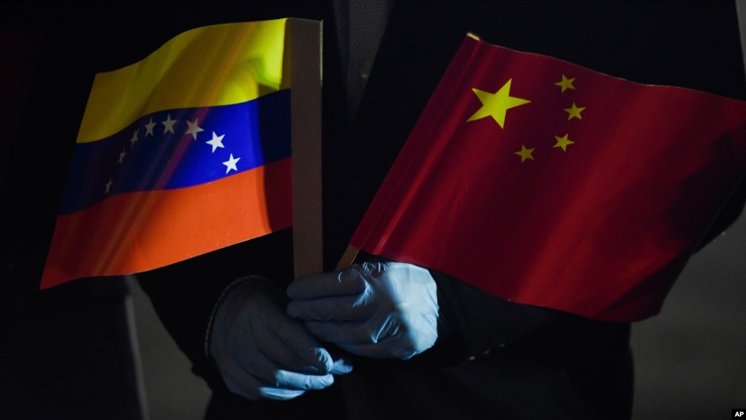 El canciller de Venezuela, Jorge Arreaza, sostiene las banderas de Venezuela y China mientras llegan especialistas médicos y suministros de China al Aeropuerto Internacional Simón Bolívar. en La Guaira, Venezuela. Marzo 30, 2020.