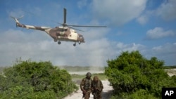 Deux soldats somaliens regardent l'arrivée d'un hélicoptère kényan, à Bur Garbo, Somalie, le 14 décembre 2011.