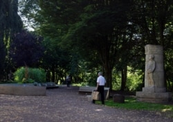 A man walks with his shopping bags past the Monument for the Congo Pioneers in Halle, Belgium, June 24, 2020. In Halle, a small trading town of 40,000, as across much of Europe, the tide is turning and a new consciousness is taking shape.