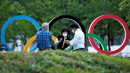 People chat next to Olympic Rings monument outside the Japan Olympic Committee (JOC) headquarters near the National Stadium, the main stadium for the 2020 Tokyo Olympic Games that have been postponed to 2021, in Tokyo, June 23, 2021. June…