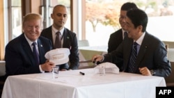 US President Donald Trump speaks with Japan's Prime Minister Shinzo Abe during a luncheon at the Kasumigaseki Country Club Gold Course in Tokyo, Nov. 5, 2017. The president and prime minister signed white hats reading “Donald and Shinzo Make Alliance Even