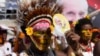 A man with a traditional headdress uses a fan to shield the sun as Pope Francis holds a holly mass at Sir John Guise Stadium in Port Moresby, Papua New Guinea, Sept. 8, 2024. 