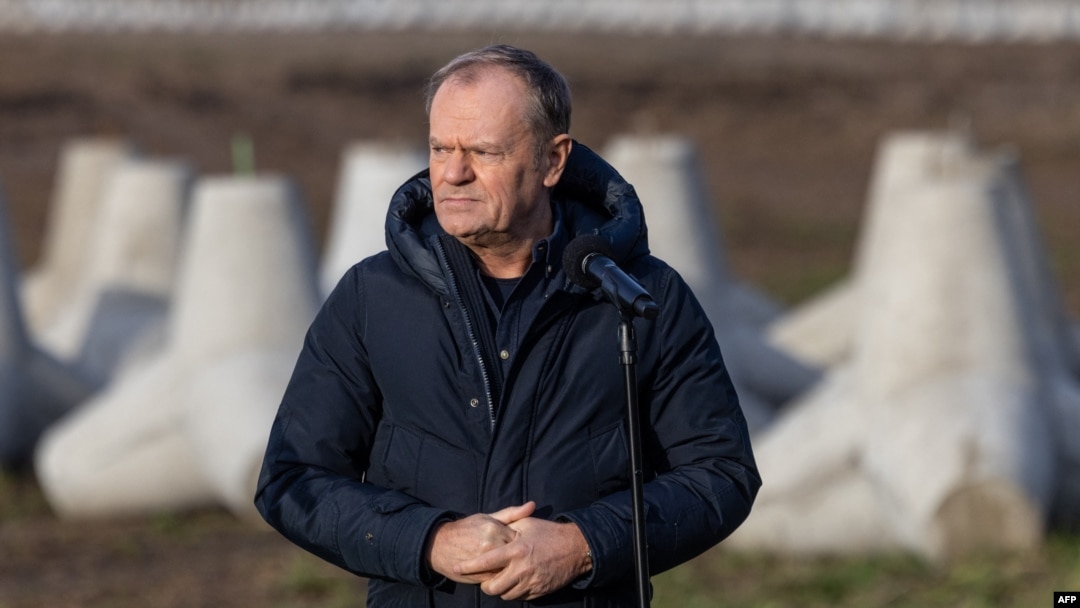 Polish Prime Minister Donald Tusk addresses reporters with concrete antitank barriers in the background during his inspection of the first completed section of fortifications on the Polish-Russian border near Dabrowka, Poland, on Nov. 30, 2024.