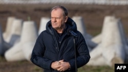 Polish Prime Minister Donald Tusk addresses reporters with concrete antitank barriers in the background during his inspection of the first completed section of fortifications on the Polish-Russian border near Dabrowka, Poland, on Nov. 30, 2024.