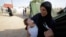 FILE- A woman who fled violence in the Iraqi town of Jalawla carries a baby at Ali Awa refugee camp, near Khanaqin city, Aug. 28, 2014. 