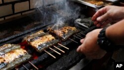 Shinji Hashimoto, sixth-generation owner of a Michelin one-star unagi restaurant in Tokyo, grills Japanese eel that has been coated in a salty-sweet soy sauce marinade, over hot charcoal, Aug. 2, 2017. The endangered Japanese summer delicacy may get a new lease on life with commercial farming.