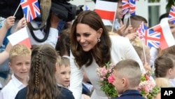 FILE - Children welcome Britain's Kate, the Duchess of Cambridge, during her visit with Prince William in front of the presidential palace, in Warsaw, Poland, July 17, 2017.