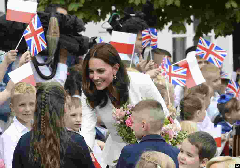 Children welcome Britain's Kate, the Duchess of Cambridge, during her visit with Prince William in front of the presidential palace, in Warsaw, Poland.