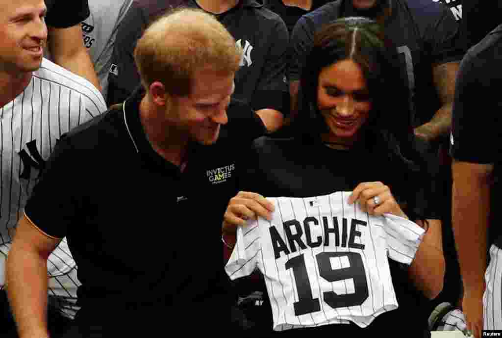 Britain&#39;s Prince Harry and Meghan, Duchess of Sussex, receive a present for baby Archie as they meet players of the New York Yankees before a match against the Boston Red Sox in London, June 29, 2019.