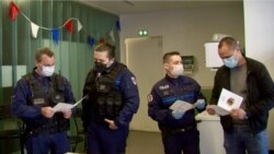 Police officers consult menu from Bistros Pas Parisiens Solidaires charity to see what they'll be eating. (Photo: Lisa Bryant / VOA)