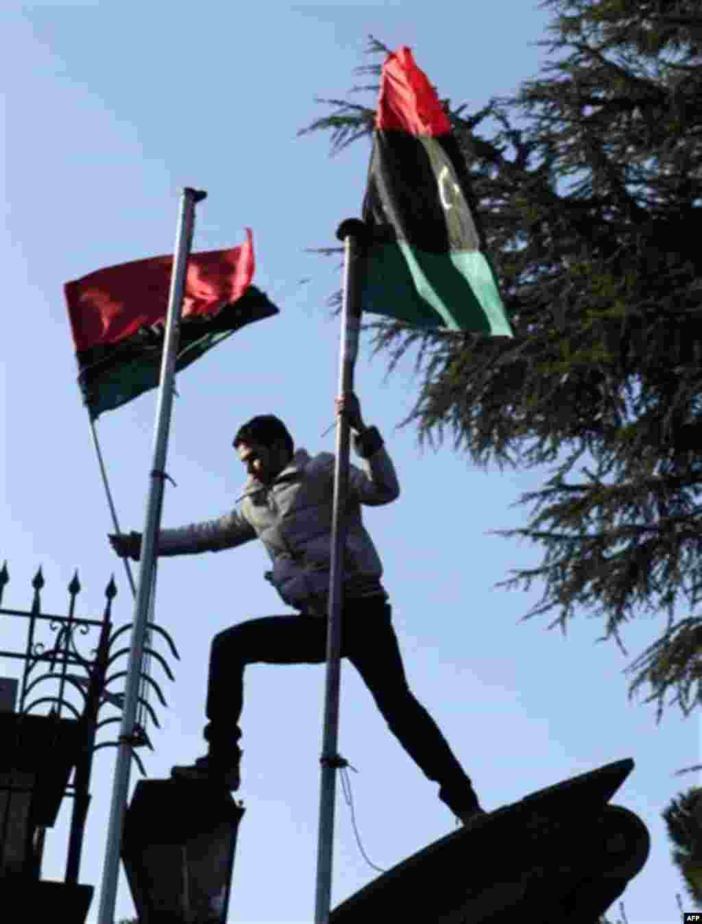 A demonstrator waves pre-Gadhafi era national flags during an anti-Gadhafi protest in front of the Libyan embassy in Rome, Wednesday, Feb. 23, 2011. (AP Photo/Pier Paolo Cito)