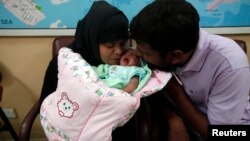 Sepasang suami istri mencium bayi mereka, Fatima, yang baru diadopsi dalam siaran televisi langsung di Pakistan (1/8).