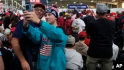 Supporters take a photo as Republican presidential nominee former President Donald Trump speaks at a campaign event at Dane Manufacturing in Waunakee, Wisconsin, Oct. 1, 2024.