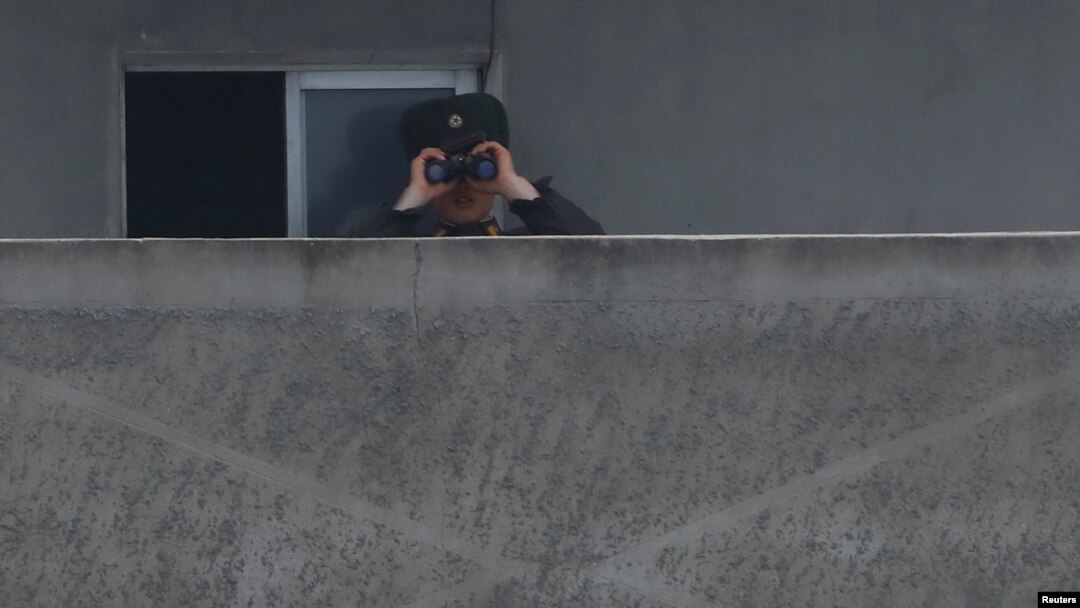 A North Korean soldier looks through a pair of binoculars at the Yalu River in Sinuiju, North Korea, which borders Dandong in China's Liaoning province, April 15, 2017.