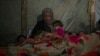 Reda Abu Zarada wraps herself and her grandchildren in blankets as they prepare to sleep in their tent at a camp in Khan Younis, Gaza Strip, Dec. 19, 2024. 