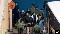 Some of the 47 pro-democracy activists including Lam Cheuk-ting, center, are escorted by Correctional Services officers to a prison van in Hong Kong, March 4, 2021.