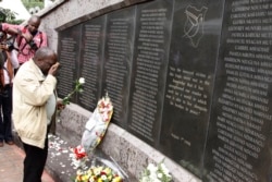 FILE - An unidentified man lays flowers at the US Embassy bombing memorial site in Nairobi, Kenya, Aug. 7, 2013.