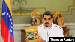 Venezuela's President Nicolas Maduro holds a book titled 'Mining Sectoral Plan' while delivering a speech during a launching of a National Mining Plan at the Miraflores palace in Caracas
