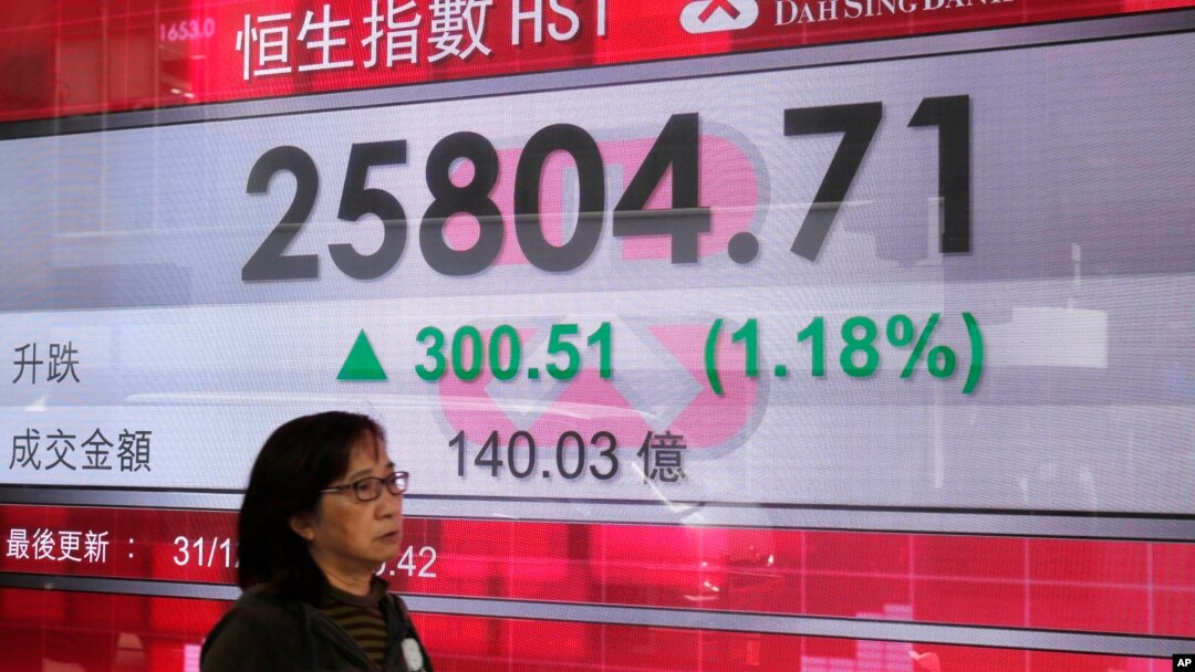 Seorang perempuan melewati papan informasi elektronik yang menunjukkan indeks gabungan di luar sebuah bank di Hong Kong, 31 Desember 2018.
