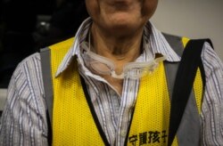 A pair of swimming goggles dangle from the neck of "Grandpa Wong," 85, as he rides an MTR train to the Tung Chung district in Hong Kong, Sept. 7, 2019.