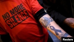 FILE - Paul Levely, a child sex abuse victim, wears a T-shirt that says "no more silence" and shows a tattoo on his arm in Rome, Italy, Feb. 28, 2016. The Catholic Church in Australia is rejecting laws forcing priests to report confessions of child abuse.