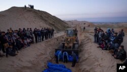 Una excavadora descarga los cuerpos de palestinos muertos en combates con Israel y entregados por el ejército israelí durante un funeral masivo en Rafah, Franja de Gaza, el 26 de diciembre de 2023.