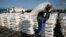 FILE - A man carries sacks of food aid for distribution to Internally displaced people (IDPs) in the POC (Protection of Civilians) Camp, run by the UN Mission in South Sudan near the town of Malakal, in the Upper Nile state of South Sudan.