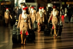 FILE - Cabin crew members, wearing face masks to prevent the spread of the coronavirus, walk along the departure hall of the Zaventem international airport in Brussels, Jan. 22, 2021.