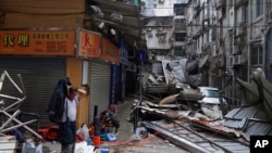 FILE - A man walks past debris from Typhoon Hato in Macau, China, Aug. 24, 2107. Hong Kong, Macau and Southern China are bracing for Typhoon Khanun, which is forecast to make landfall early Monday.