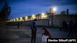 Migrant workers stand by the barbed wire fence of the IK-3 penal colony where jailed Kremlin critic Aleksey Navalny was reportedly transferred in the city of Vladimir, April 19, 2021.